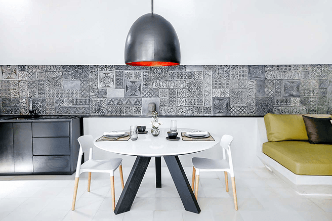 Modern Bali villa dining area with patterned tile backsplash, black pendant lamp, and round table setup for two.