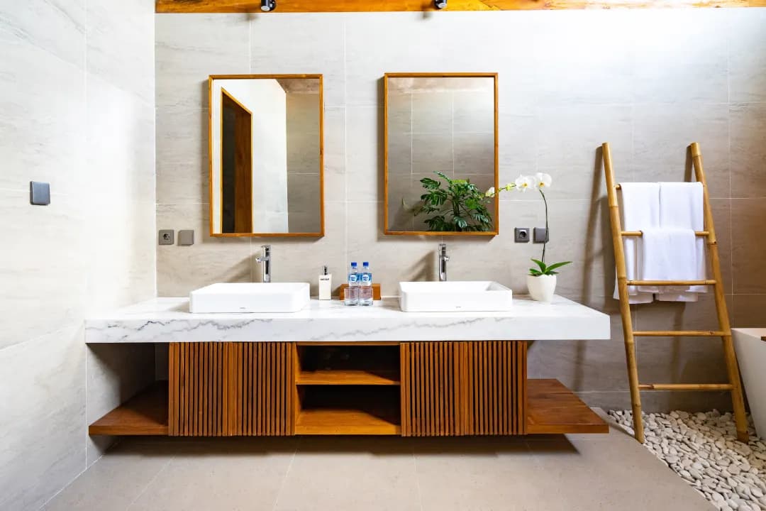 Elegant bathroom in bedroom three at Jiwoku Villas Canggu Bali featuring double vanity with marble countertop, wooden accents, and orchid plant decoration