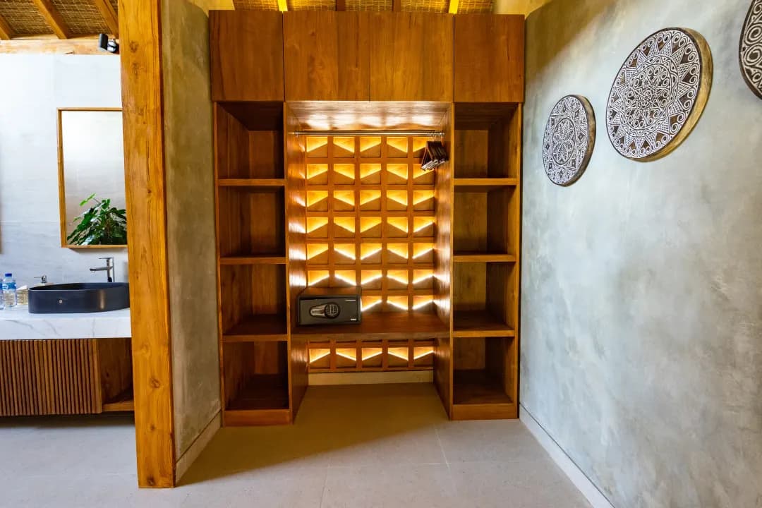 Wardrobe area in bedroom three at Jiwoku Villas Canggu Bali with wooden shelves, safe, and bathroom access
