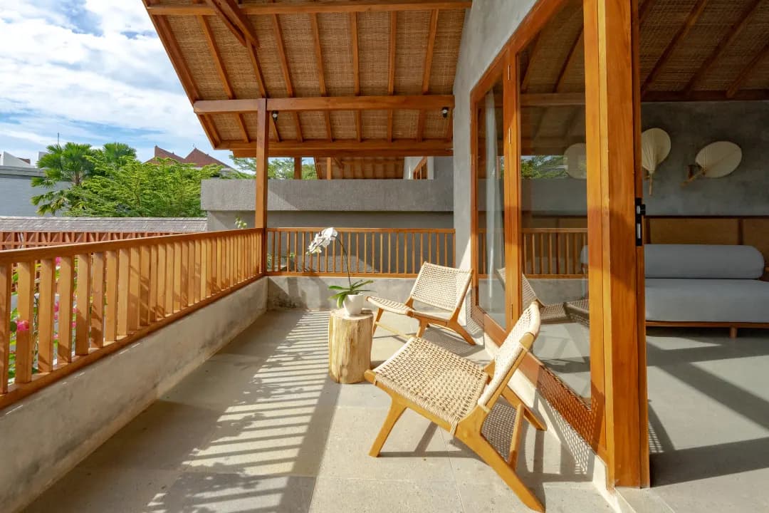 Balcony of bedroom three at Jiwoku Villas Canggu Bali with wooden chairs and tropical garden view
